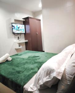 a bedroom with a bed and a flat screen tv at JRJA Suites 2 fronting St Mary's College Tagum in Tagum