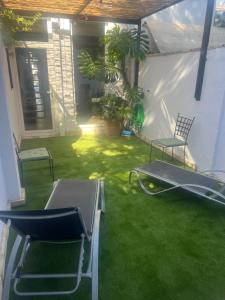 a patio with a lawn with chairs and a swing at Brisas a un paso del centro in Valencina de la Concepción