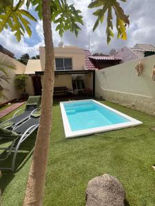 una piscina en el patio de una casa con una palmera en La Casita del Tío Juan, en Morro del Jable