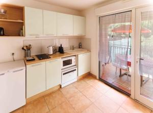a kitchen with white cabinets and a large window at Orangeraie du Cap d'Antibes in Antibes