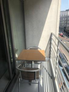 einen Holztisch und einen Stuhl auf dem Balkon in der Unterkunft Stijlvol Appartement vlakbij Strand & Casino Vakantie Odyssey Oostende in Ostende