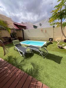 un par de sillas de jardín sentadas junto a una piscina en La Casita del Tío Juan, en Morro del Jable