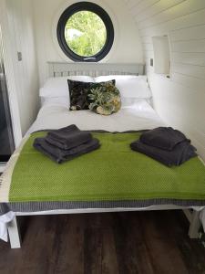 a bed in a small room with towels on it at Orielton Fach Farm - Cosy rural lodge in beautiful surroundings in Pembrokeshire