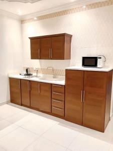a kitchen with wooden cabinets and a microwave at Al Quba Palace Serviced Apartments in Riyadh