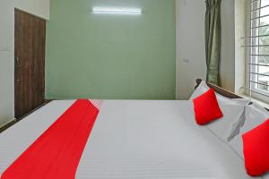 a bedroom with a bed with red pillows on it at Hotel O M & M Hospitality in Bengaluru