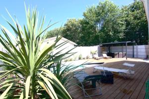 a wooden deck with tables and chairs and a plant at Villa Coquillage in Le Teich