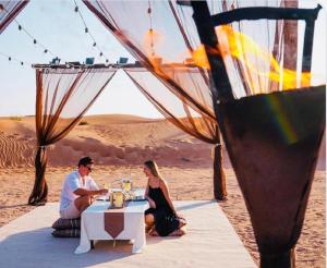 山姆Desert island Camp & Resort Jaisalmer的坐在沙漠桌子上的男人和女人