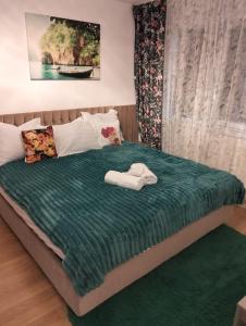 Una cama con una manta verde y dos toallas. en Mony Apartaments, en Roman