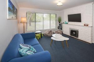 a living room with a blue couch and a fireplace at Haven By the Bay- Short walk to Broadwater beach in Broadwater