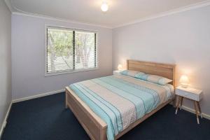 a white bedroom with a bed and a window at Haven By the Bay- Short walk to Broadwater beach in Broadwater