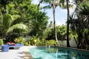 a swimming pool in a resort with palm trees at Nativ Lodge and Spa in Mahébourg