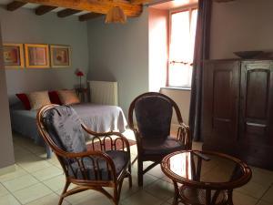 1 dormitorio con 2 sillas, 1 cama y 1 mesa en Chambres d'Hôtes Les laitières en Beaurepaire