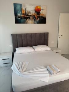 a bedroom with a white bed with a painting on the wall at DG Apartment in Golem