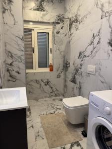 a bathroom with a toilet sink and a washing machine at DG Apartment in Golem +4 photos