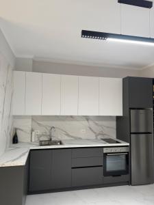 a kitchen with white cabinets and stainless steel appliances at DG Apartment in Golem