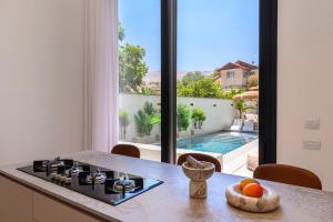 cocina con fogones y vistas a la piscina en אחוזת דוד - וילה יוקרתית עם בריכה פרטית מחוממת ומקורה, en Hatzor haglilit