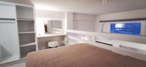 a white bedroom with a bed and a window at Mairyren Luxury apartment in Ano Syros