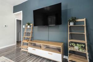 a living room with a flat screen tv on a blue wall at The Downtown Delight - New Corporate Apt Downtown in Grand Rapids