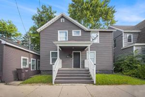 a gray house with a staircase leading to the front door at The Downtown Delight - New Corporate Apt Downtown in Grand Rapids