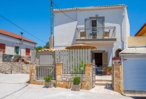 a white house with a fence and an umbrella at Arokaria Studios by PaxosRetreats in Gaios