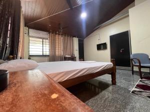 a bedroom with a large bed and a table in it at Eesha Residency Udupi in Udupi