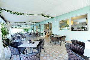 a restaurant with tables and chairs and windows at Hotel Itta in Caorle