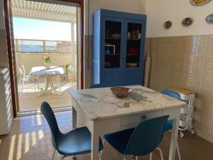 a kitchen with a table and blue chairs and a dining room at Terrazza delle Sirene - Fronte mare Pozzallo in Pozzallo