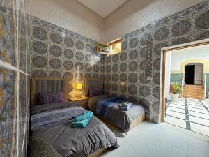 a bedroom with two beds and a wall covered in moroccan tiles at Riad Dar Fassi in Rabat