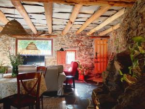 a living room with a table and chairs and a stone wall at El Carpintero in Trevélez