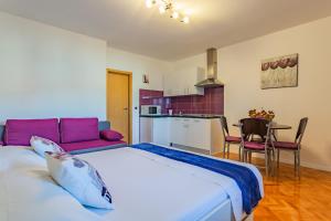a bedroom with a large bed and a kitchen at Apartment Bonaca in Posedarje