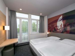 a hotel room with a bed and a desk and window at B&B HOTEL Berlin-Adlershof in Berlin +24 photos