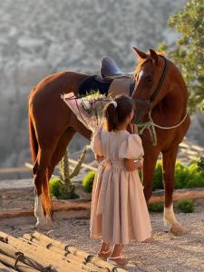 a little girl standing next to a brown horse at Dana luxury huts in Dana
