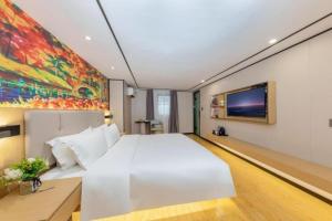 una camera da letto con un letto bianco e un quadro sul muro di Yimimi Apartment - Guangzhou 13th Line Yide Road Metro Station a Canton
