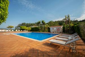 a swimming pool with a chaise lounge and a bench at Apartamentos Casa Ameirós in O Grove
