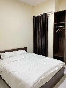 a bedroom with a white bed and a black curtain at Alya Villa Syariah in Sidoarjo +8 photos
