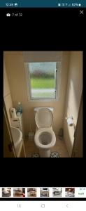 Un pequeño baño con inodoro y ventana. en Cosy holiday home, en Warden