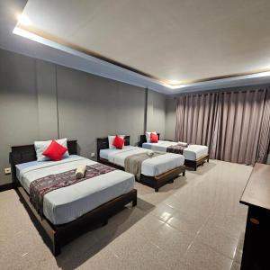 a hotel room with three beds with red pillows at Ridho Malik Hotel in Bumbang