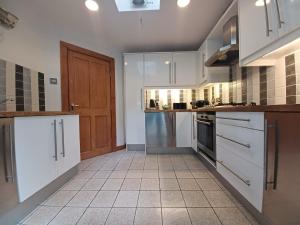 a kitchen with white cabinets and a tile floor at Duddon Valley Retreat, Lake District National Park, Sleeps 7 in Broughton in Furness