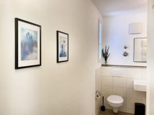 a bathroom with a toilet and three pictures on the wall at Wohnliches Design Apartment in schöner Lage nahe Ulm & Science Park in Blaustein +19 photos