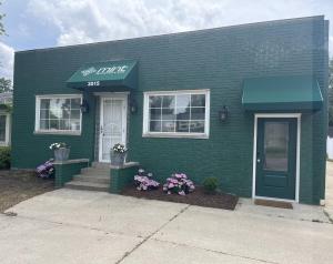 a green building with a white door and flowers at Ripple Avenue Suites Suite B in Indianapolis