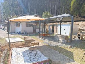 a patio with chairs and umbrellas in front of a house at Potontoikkenya Kuraoka - Vacation STAY 23373v in Mamihara