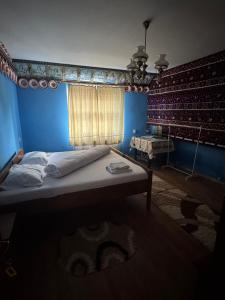 a bed in a blue room with a window at Casa Vlad-Alex in Săpânța