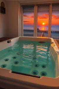 a jacuzzi tub with a view of the sunset at L’annexe sur mer in Le Portel