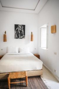 Un dormitorio blanco con una cama y una mesa. en Riad THALGE, en Marrakech
