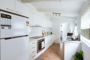een witte keuken met witte kasten en apparaten bij 3BR CBD Aircon Redfern family home in Sydney +35 foto's