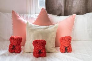 een groep kussens op een bed met rode rozen bij 3BR CBD Aircon Redfern family home in Sydney