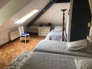 a attic bedroom with two beds and a chair at Villa Marie SAPHIR in Verton