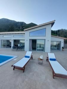 ニドリにあるVilla Ninemiaのラウンジチェア2脚とプールが備わる家