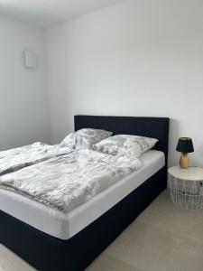 a bed with a black frame and white sheets and pillows at Moderne Ferienwohnung nahe Worpswede und Bremen-stilvoll & zentral in Lilienthal