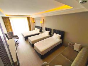 een hotelkamer met twee bedden en een bank bij PETRA HOTEL TUZLA in Tuzla